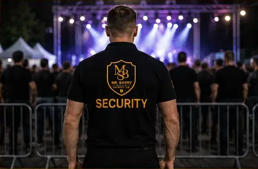 Uniformed security officer monitoring event barriers in front of a lit stage